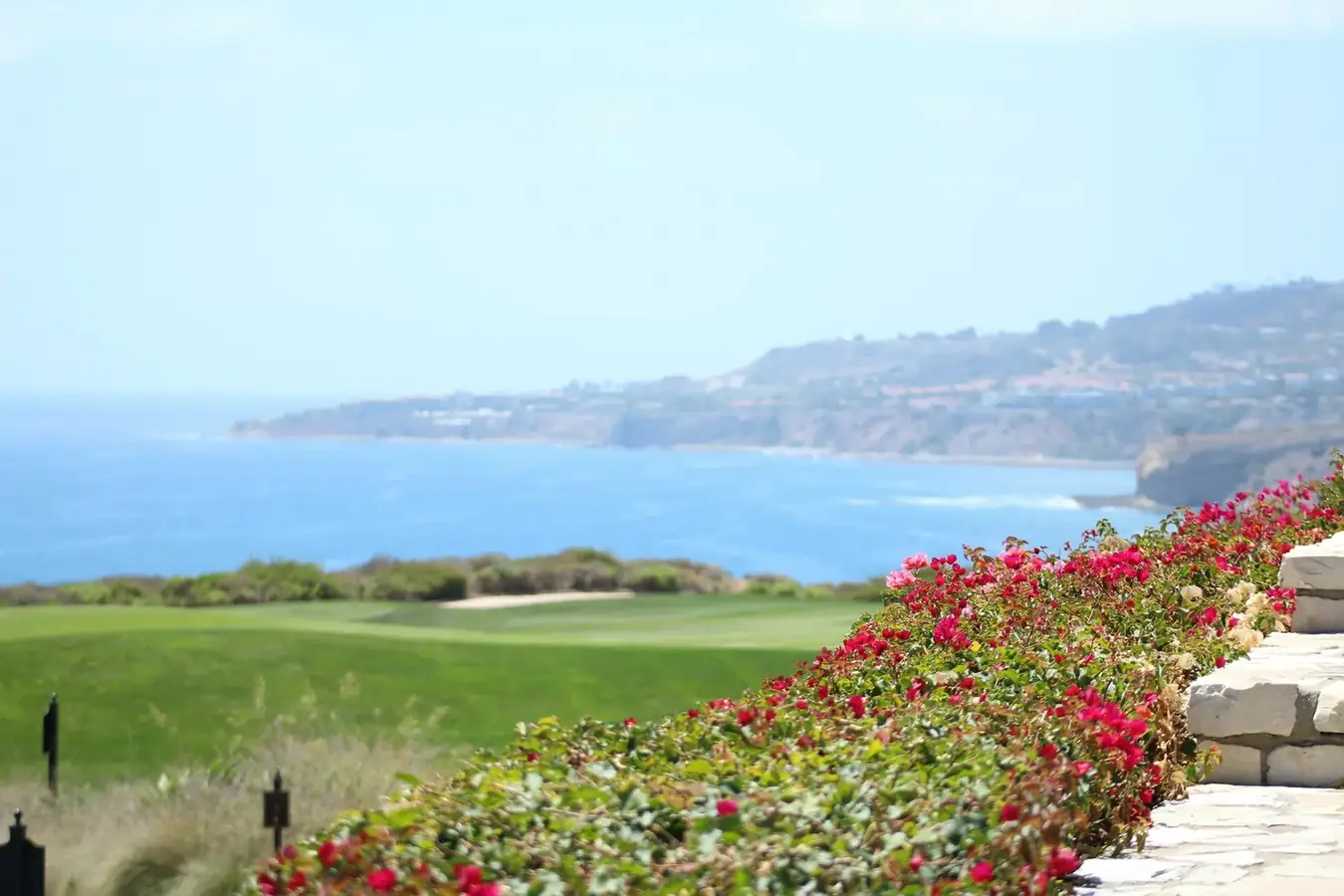 A coastal golf course framed by flowering landscaping