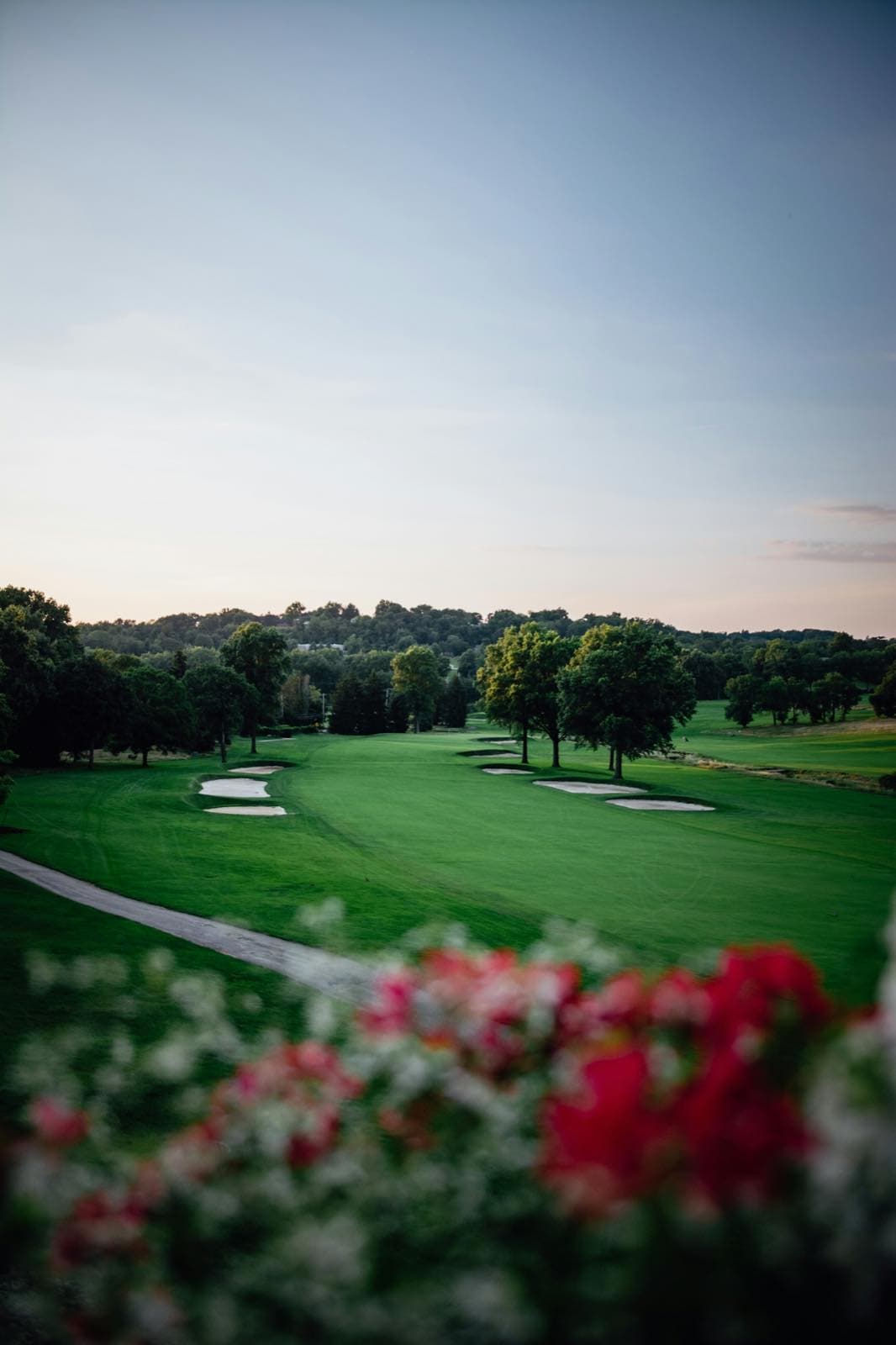 A manicured golf fairway framed by red and white flowers